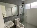 Modern bathroom with glass shower, toilet, and wall-mounted sink