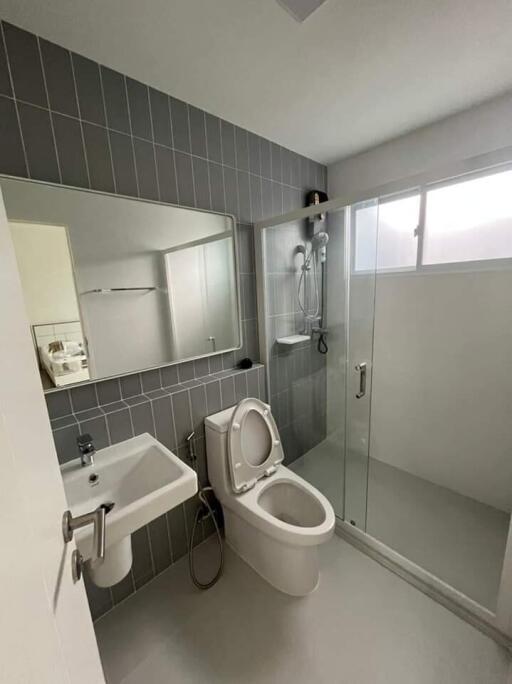 Modern bathroom with glass shower, toilet, and wall-mounted sink