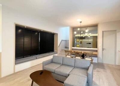 Modern living room with grey sofa, wooden coffee table and dining area