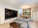 Modern living room with grey sofa, wooden coffee table and dining area