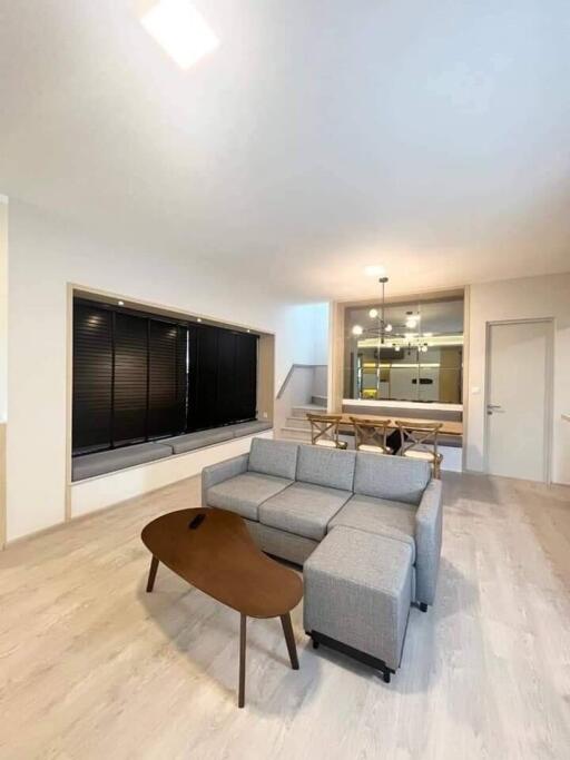 Modern living room with grey sofa, wooden coffee table and dining area