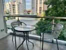 Modern balcony with a glass table and two chairs overlooking urban skyline and greenery