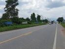 Photo of a paved road with vehicles and surrounding greenery