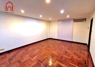 Spacious empty bedroom with wooden flooring and ceiling lights.