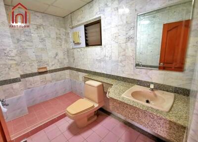 Bathroom with marble tiles, pink sink and toilet, and large mirror