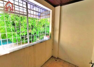 Small balcony with barred window and plants outside