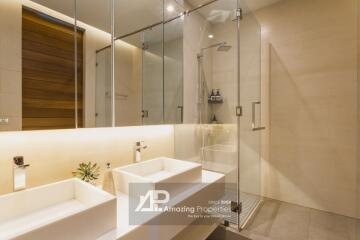 Modern bathroom with double sinks, large mirrors, and a walk-in shower