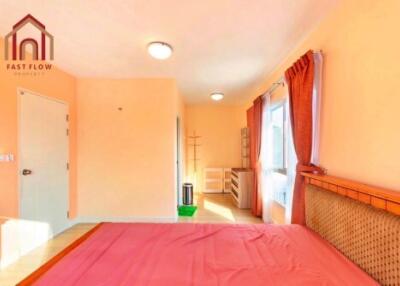 Bright bedroom with pink bedspread and ample natural light