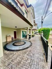 Front view of the building showing an entrance, a patio with circular tile design, and a gate