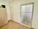 Bedroom with wooden floor, wardrobe, door, and large window