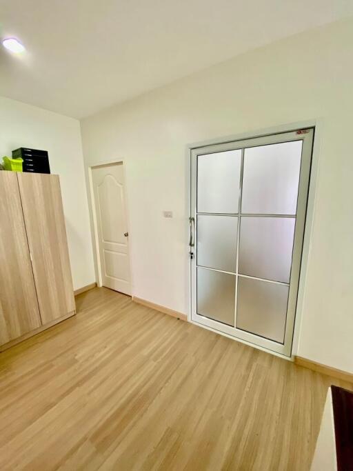 Bedroom with wooden floor, wardrobe, door, and large window