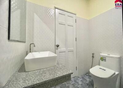 A modern bathroom featuring a vanity with a vessel sink, a wall-mounted mirror, and a toilet.