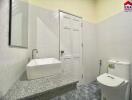 A modern bathroom featuring a vanity with a vessel sink, a wall-mounted mirror, and a toilet.