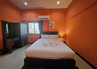 Modern bedroom with orange walls, a double bed, wardrobe, and air conditioning unit