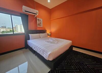 Spacious bedroom with large bed and vibrant orange walls