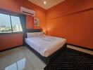 Spacious bedroom with large bed and vibrant orange walls