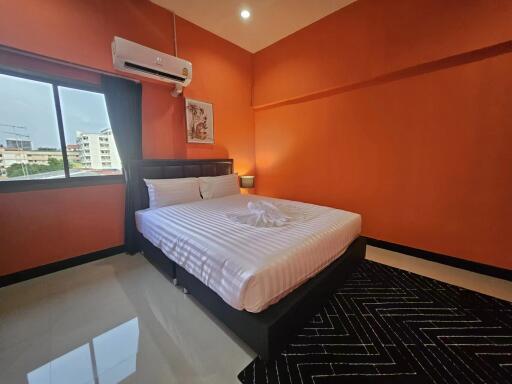 Spacious bedroom with large bed and vibrant orange walls