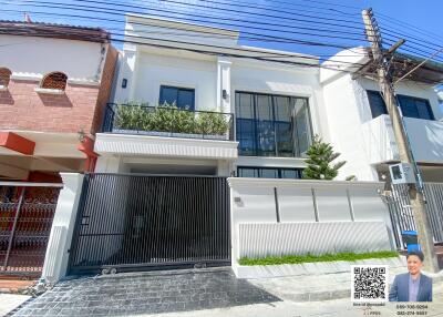 Modern two-story white house with a balcony and gated entrance