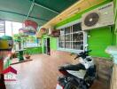 Outdoor area with green walls, tiled floor, bird cages, and a parked motorbike