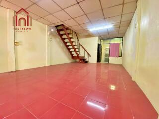 Spacious living area with red tiled floor and stairway