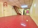 Spacious living area with red tiled floor and stairway