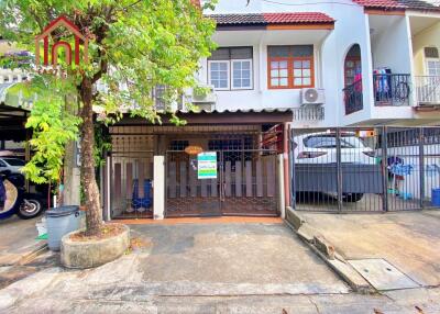 Front view of a townhouse with a small gated area and a tree