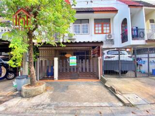 Front view of a townhouse with a small gated area and a tree