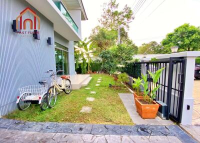 Exterior view of a house with bikes, a garden, and a gate