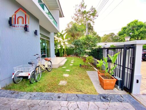 Exterior view of a house with bikes, a garden, and a gate