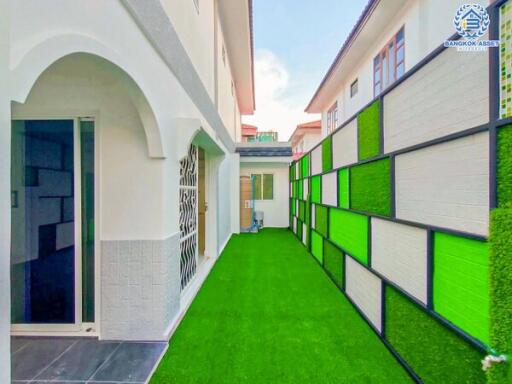 Exterior walkway with vibrant green artificial grass and colorful wall panels