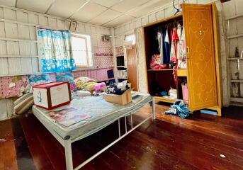 Bedroom with wooden floors, open wardrobe, and a window with colorful curtains