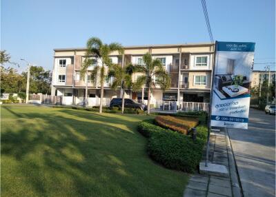 Exterior view of a multi-story residential building with landscaped lawn and trees