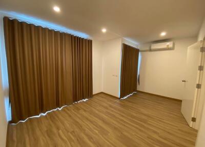 empty bedroom with wooden flooring, curtains, and air conditioning unit