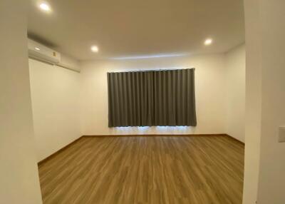 Spacious living room with wooden flooring and a large window with curtains