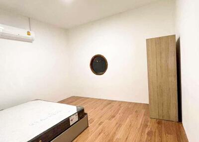 Minimalistic bedroom with wooden flooring and a round window