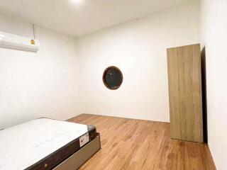 Minimalistic bedroom with wooden flooring and a round window