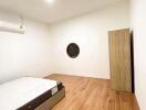 Minimalistic bedroom with wooden flooring and a round window