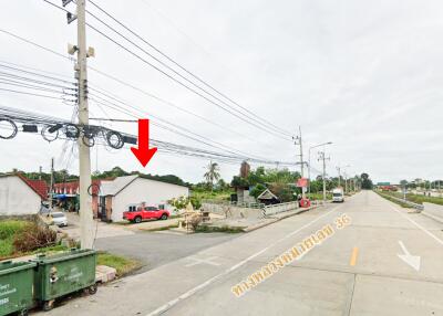 Photo of a building by the roadside with electrical wires and a red truck parked nearby