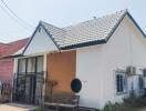 Exterior view of a single-story house with white walls and a tiled roof