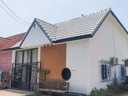 Exterior view of a single-story house with white walls and a tiled roof