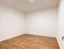 Minimalistic empty room with hardwood floors and white walls