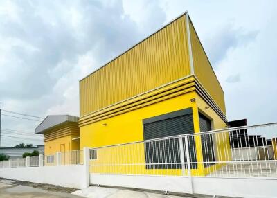 Exterior view of a modern yellow building with a white fence