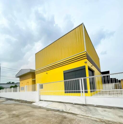 Exterior view of a modern yellow building with a white fence