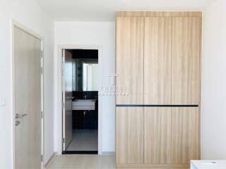 Bedroom with wooden wardrobe and view into bathroom