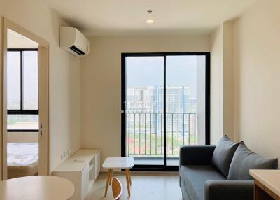 Bright living room with sofa, coffee table, TV cabinet, and large windows overlooking cityscape