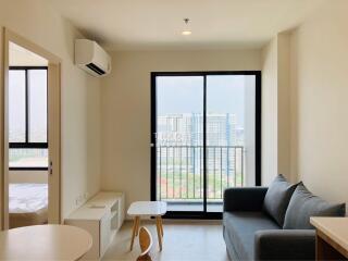 Bright living room with sofa, coffee table, TV cabinet, and large windows overlooking cityscape