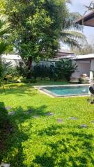 Tranquil backyard with a well-maintained lawn, pool, and lush greenery