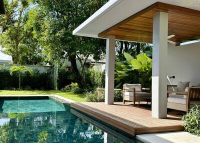 Modern outdoor seating area beside a pool with lush greenery