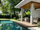 Modern outdoor seating area beside a pool with lush greenery