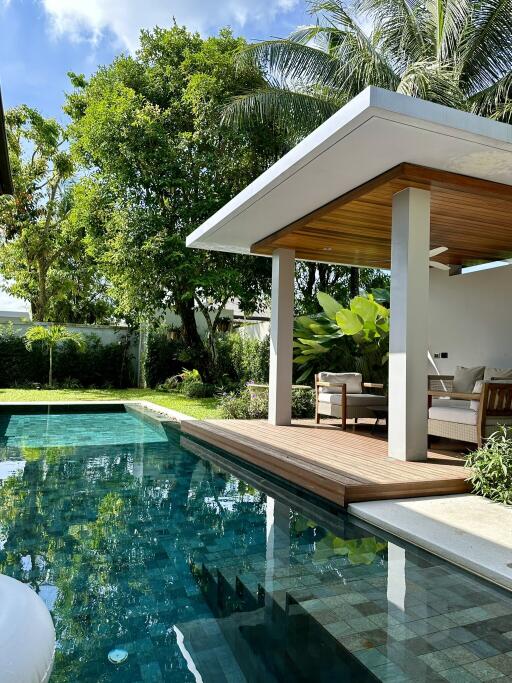 Modern outdoor seating area beside a pool with lush greenery